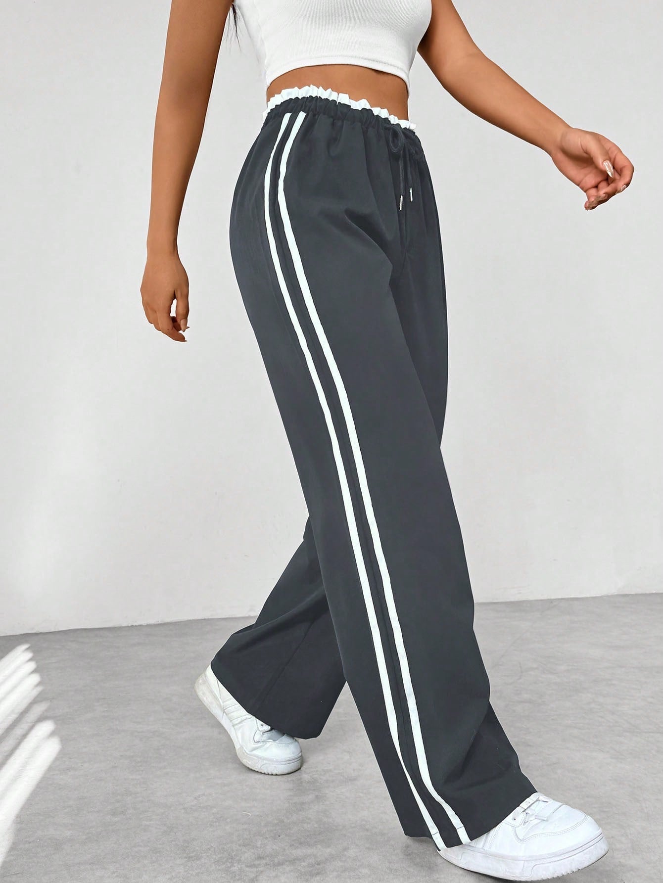 Close-up van de trendy strepen op deze sportieve wide-leg damesbroek, accentueert het streetwear design.